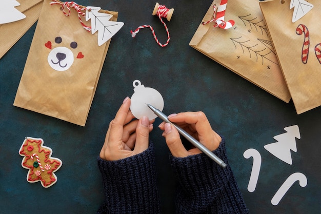 Free Photo flat lay of hands decorating christmas gift bags