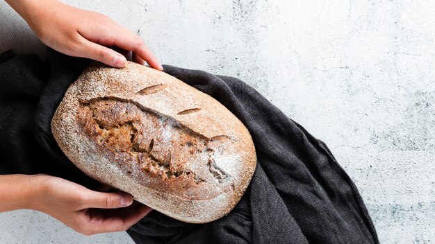 Flat lay of hands holding bread on cloth