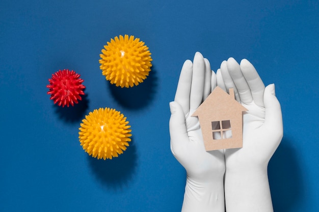 Free photo flat lay of hands with gloves holding and protecting house from viruses