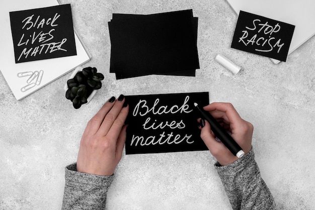 Flat lay of hands writing black lives matter on card