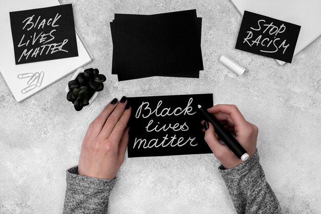 Flat lay of hands writing black lives matter on card