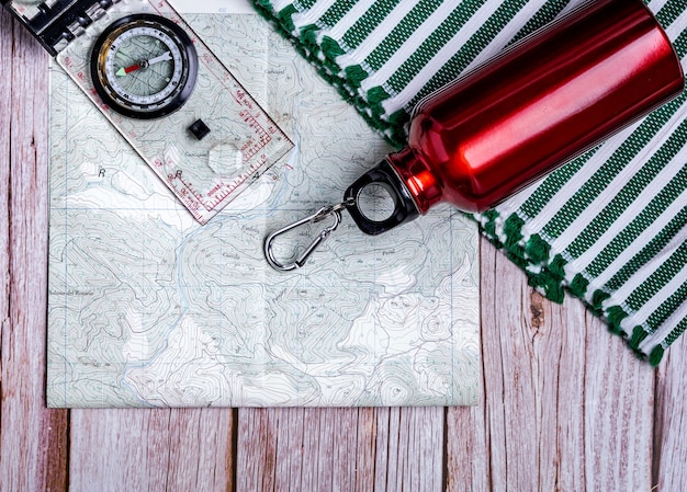 Free photo flat lay of hiking equipment - map, bottle, and compass