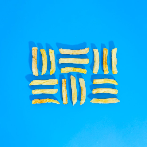 Flat lay of lined fries on blue background