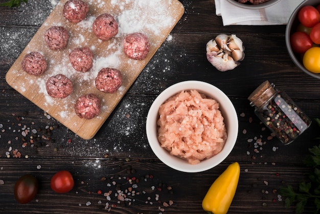 Free photo flat lay meatballs on wooden board and minced meat