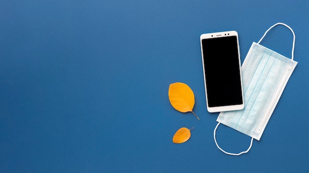 Flat lay of medical mask with smartphone and copy space