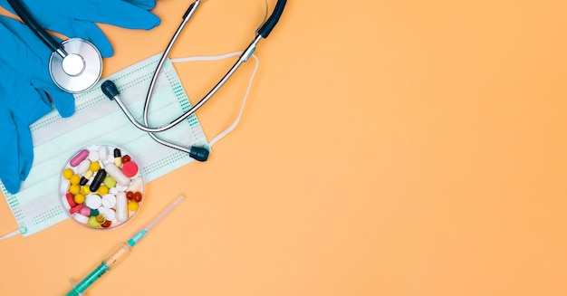 Flat lay medical mask with stethoscope and pills