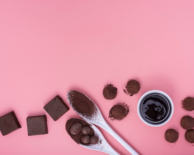 Flat lay mix of chocolate sweets on pink background with copy space