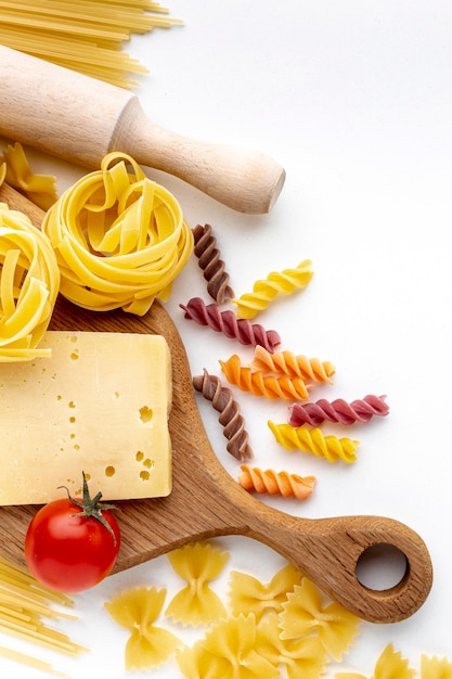 Flat lay mix of uncooked pasta with tomatoes and hard cheese