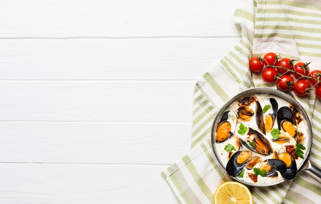 Free photo flat-lay mussels in white sauce and sides on tablecloth with copyspace