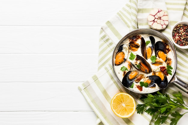 Free photo flat-lay mussels in white sauce and sides on tablecloth with copyspace