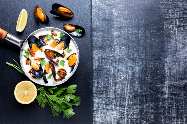 Flat-lay mussels in white sauce on slate with copyspace