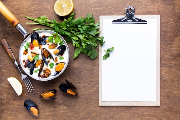 Free photo flat-lay mussels in white sauce on tablecloth with clipboard