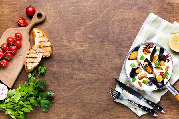 Flat-lay mussels in white sauce on tablecloth with copyspace