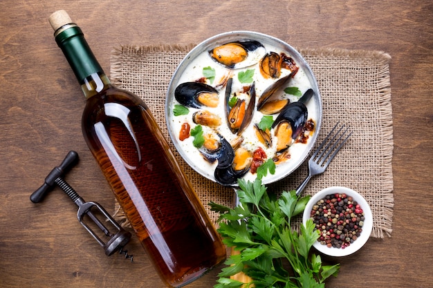 Free photo flat-lay mussels in white sauce and wine bottle