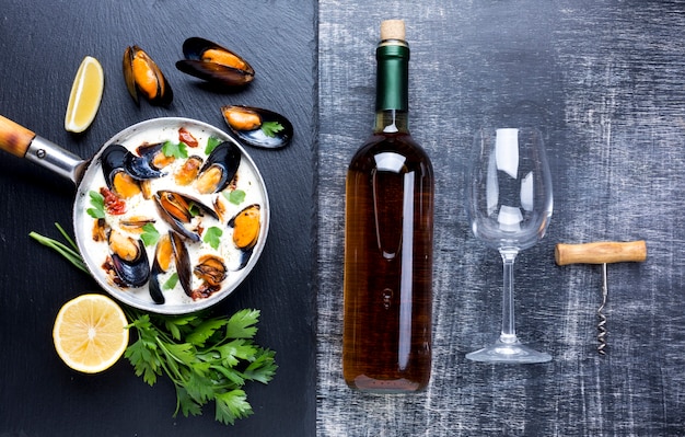 Free photo flat-lay mussels in white sauce and wine bottle