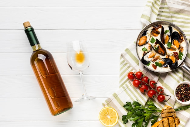 Free photo flat-lay mussels in white sauce and wine bottle