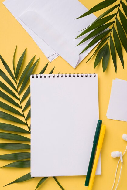 Flat lay of notebook on desk with leaves