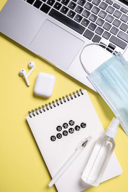 Flat lay of notebook next to medical mask with hand sanitizer