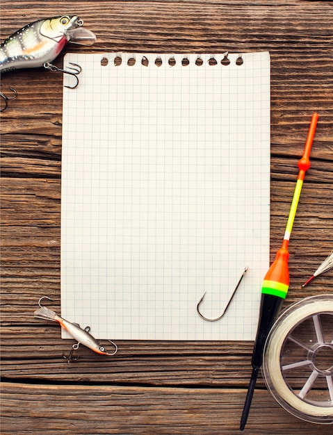 Flat lay of notebook with fishing essentials and equipment