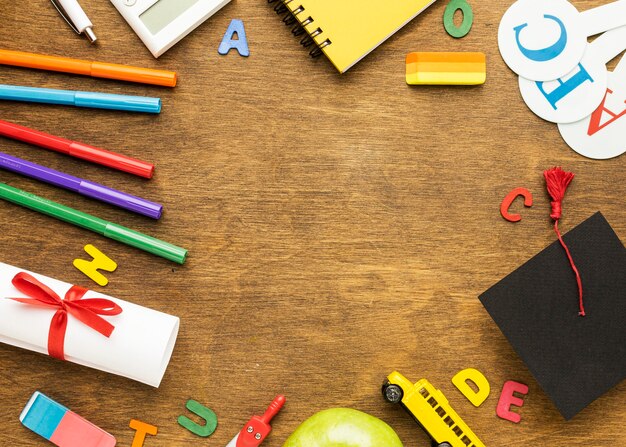 Flat lay of notebook with school supplies and diploma