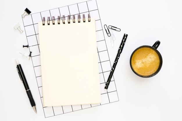 Flat lay of office stationery with coffee and pens