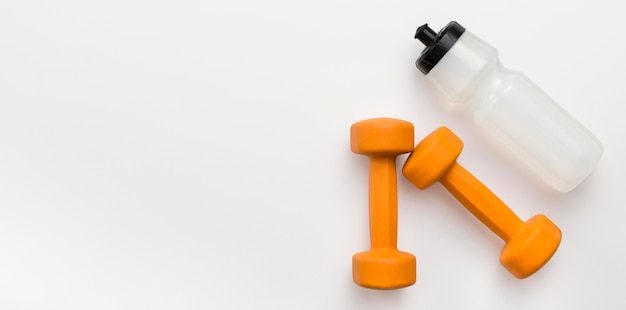 Free Photo flat lay of orange weights with water bottle and copy space