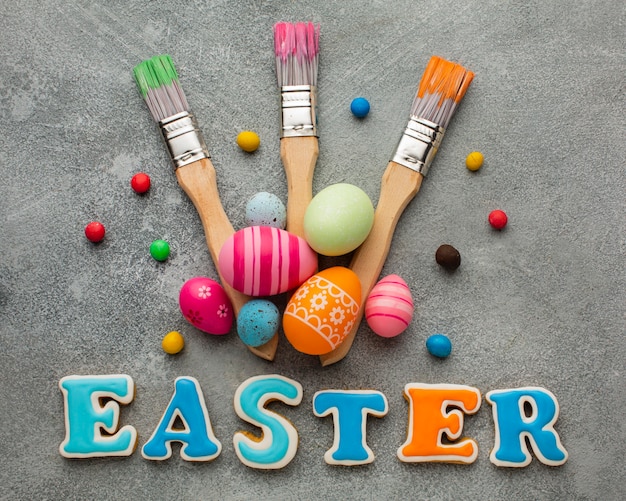 Free photo flat lay of paint brushes with colorful easter eggs