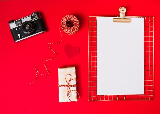 Flat lay of photo camera and blank paper