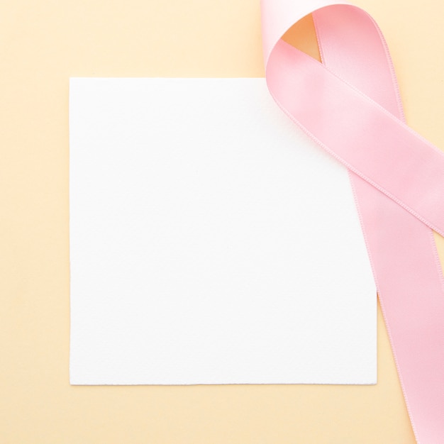 Free photo flat lay piece of paper with pink ribbon