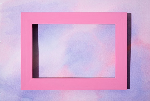 Free photo flat lay pink frame on hand painted background