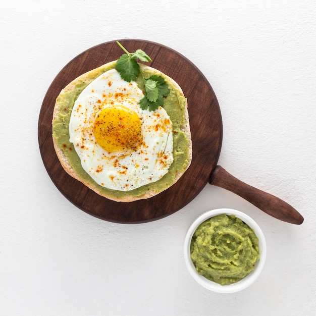 Free photo flat lay pita with avocado spread and fried egg on cutting board