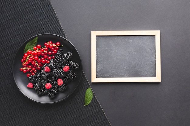 Free photo flat-lay plate of fresh berries with blackboard