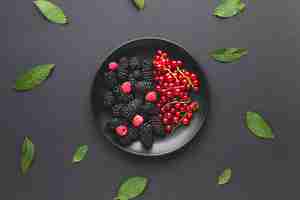 Free photo flat-lay plate of fresh berries with leaves