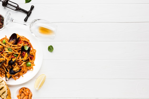 Flat-lay plate of mussels pasta and wine glass with copyspace