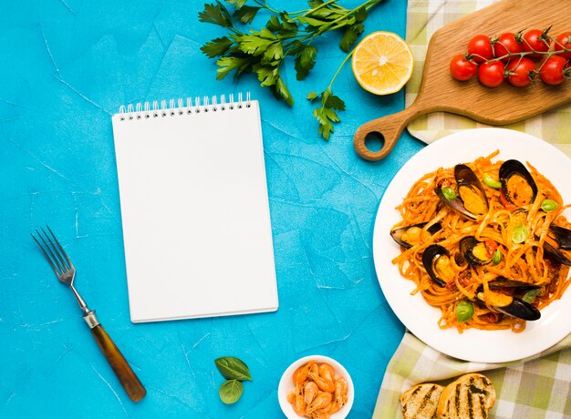 Flat-lay plate of mussels pasta with notebook