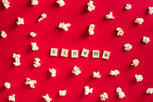 Free Photo flat lay popcorn on red background with cinema lettering