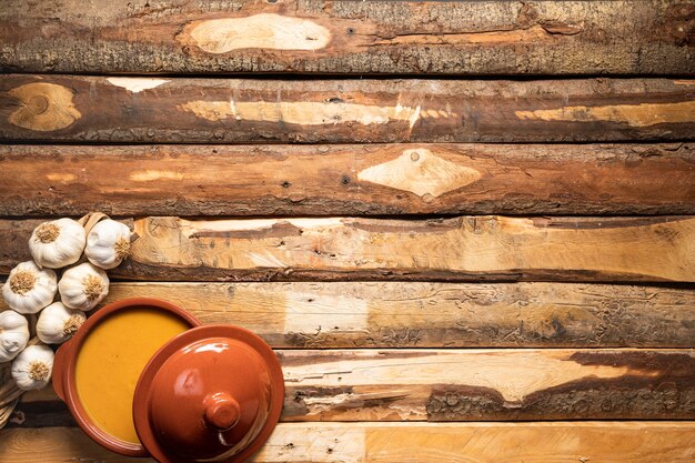 Flat lay pumpkin soup and garlic on wooden background