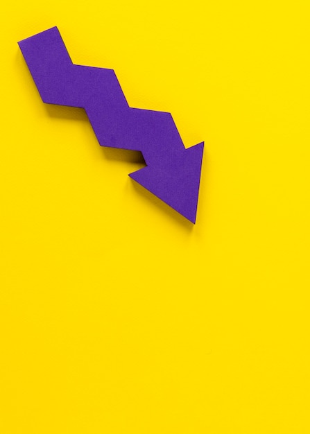 Flat lay purple arrow on yellow background with copy-space