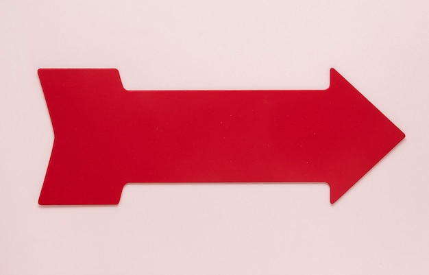 Flat lay red arrow on pink background