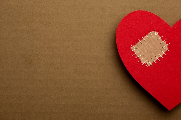 Free photo flat lay red heart with patch on cardboard background