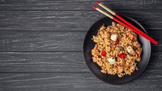 Flat lay rice with vegetables on plate and chopsticks with copy space