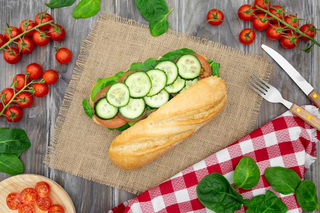 Flat lay of sandwich with cucumber slices and cutlery