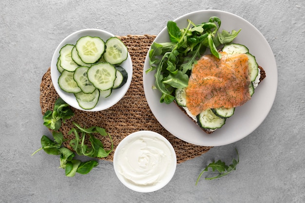 Free photo flat lay sandwich with cucumbers and salmon on plate with spinach