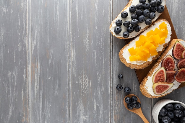 Flat lay sandwiches with cream cheese and fruits with copy-space