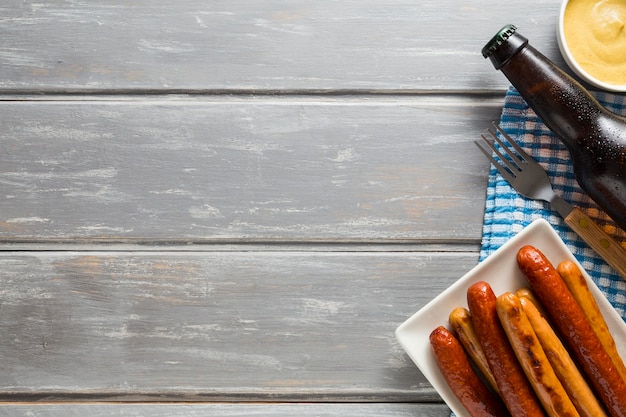 Free photo flat lay of sausages with beer bottle and copy space