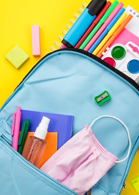 Free photo flat lay of school essentials with backpack and hand sanitizer