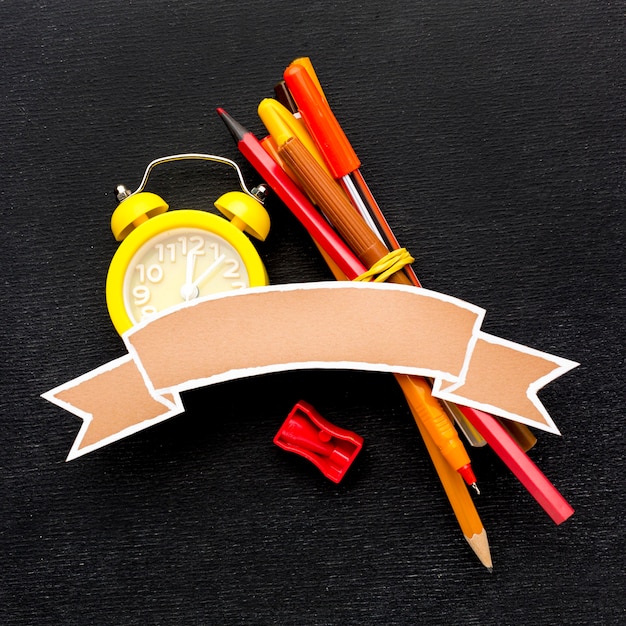 Free photo flat lay of school essentials with clock and pencils