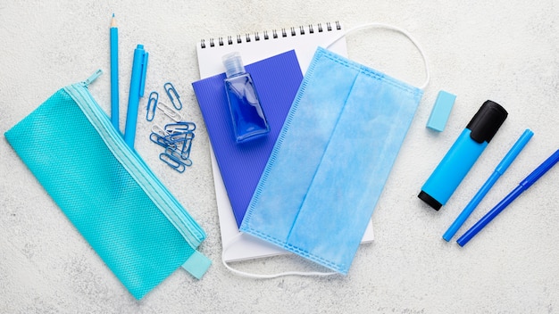 Free photo flat lay of school essentials with notebook and medical mask