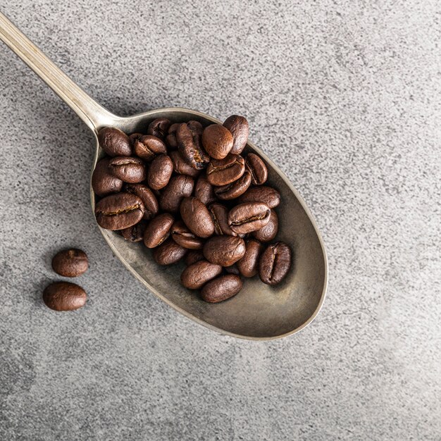 Flat lay of silver spoon with coffee beans