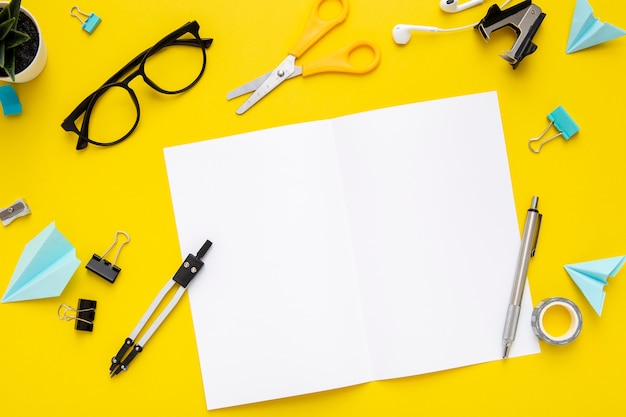 Free Photo flat lay stationery arrangement on yellow background with empty notebook